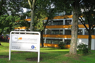 BSZ für Technik III "Richard-Hartmann" Chemnitz Facade of the Richard-Hartmann Vocational School for Technology III in Chemnitz with a white information sign in front and trees on a grassy area.