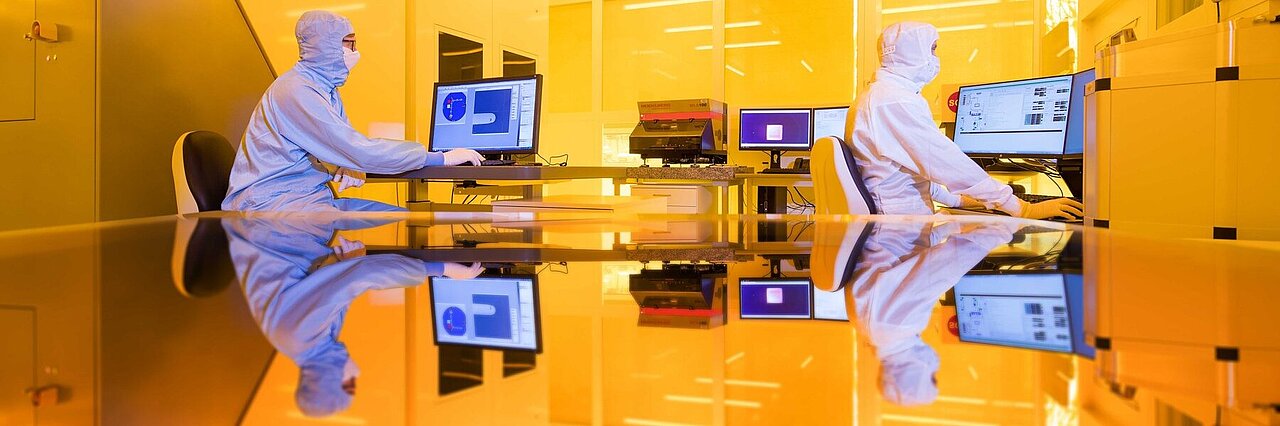 Two scientists working in yellow light of the clean room