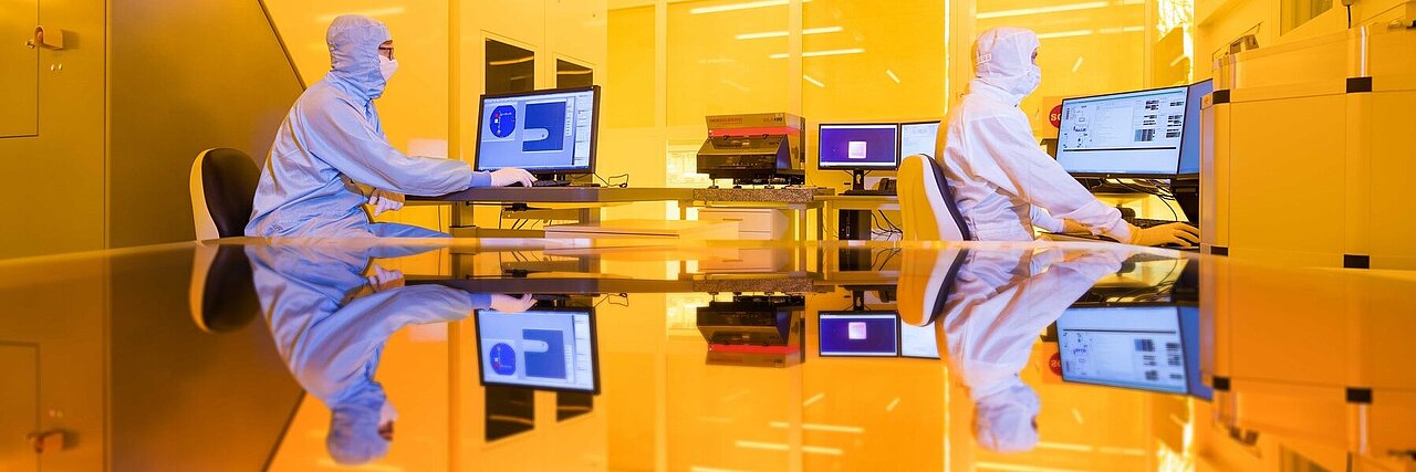 Two scientists working in yellow light of the clean room