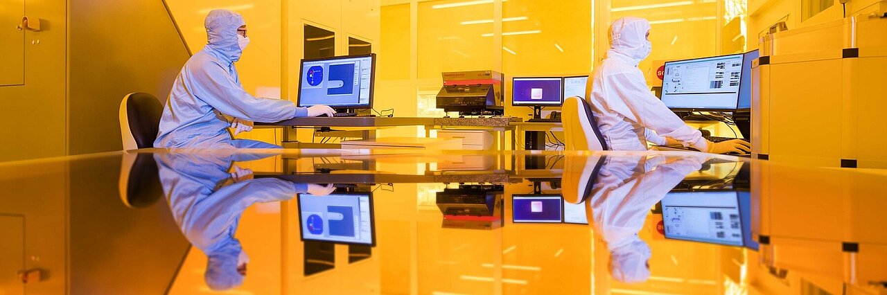 Two scientists working in yellow light of the clean room