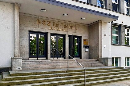 BSZ für Technik "Gustav-Anton-Zeuner" Dresden Entrance area of a building with wide stairs, three glass doors, and the inscription 'BSZ für Technik G.A. Zeuner' above the entrance.