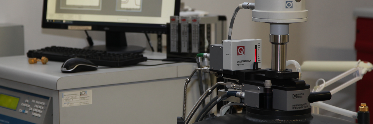 Laboratory device with measuring probe on round black housing in front of a monitor displaying graphs.