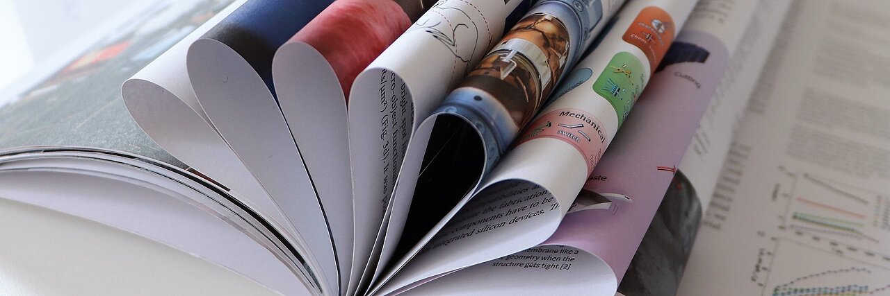 Open report with multiple folded pages on a white table.