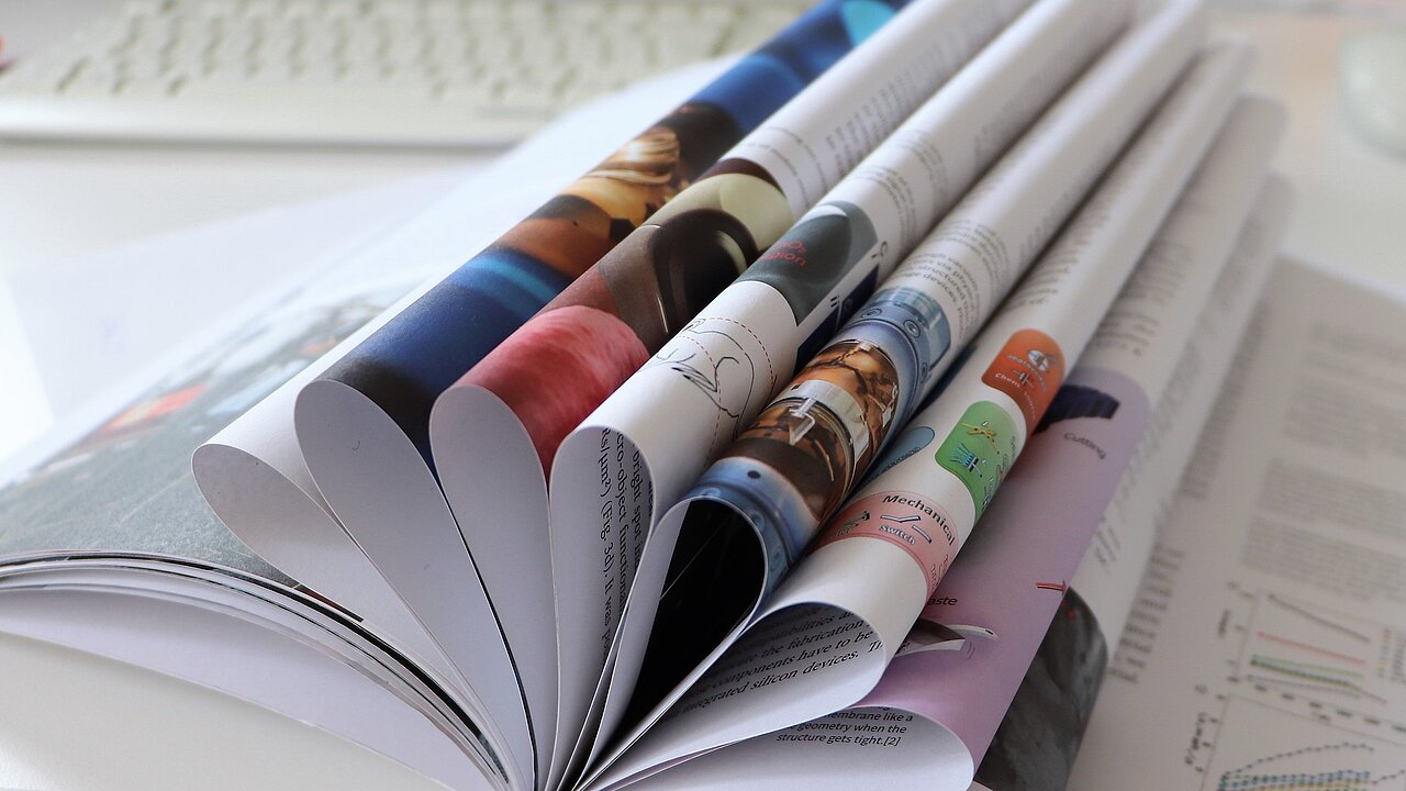 Open report with multiple folded pages on a white table.