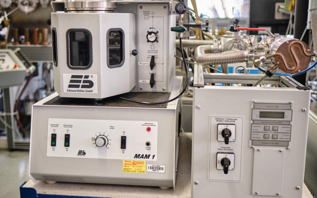 Laboratory device with control elements, knobs, and displays for a vacuum casting system in a workshop setting.