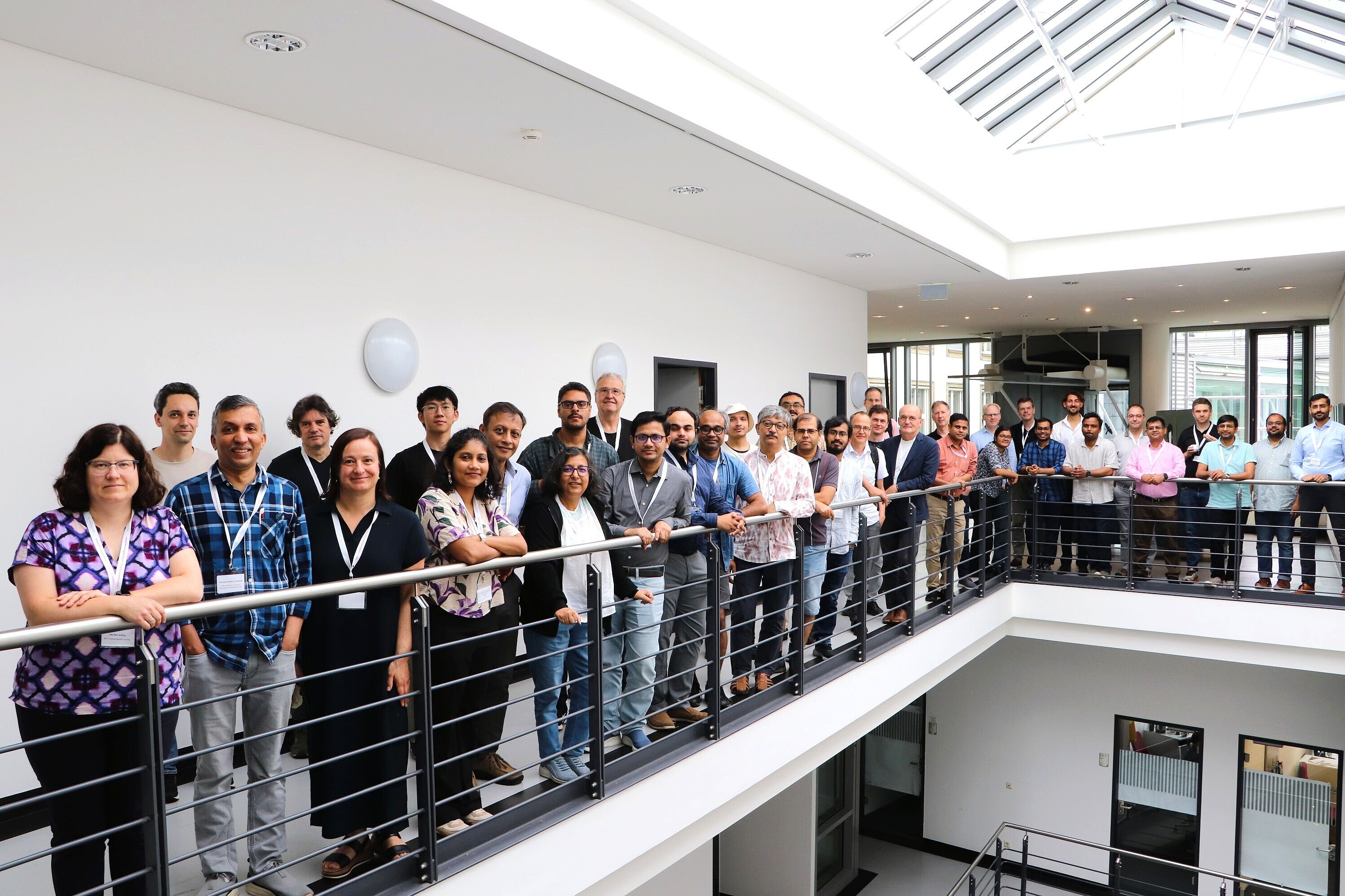 Group photo of around 40 participants of the Indo-German Workshop "Quantum Sensing with Quantum Materials: Present and Future." The group stands along the gallery of the bright atrium at IFW Dresden, facing the camera.