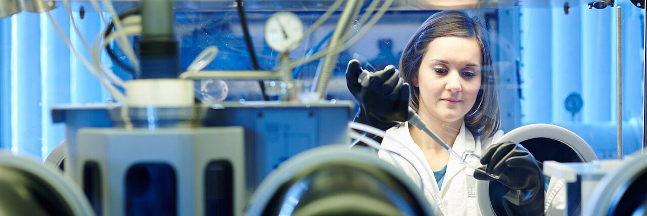 Woman wearing gloves working in a laboratory with technical equipment and gauges.