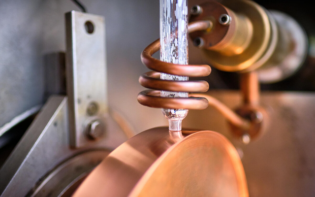 Close-up of a rotating disc with a spiral-shaped copper coil during the melt-spinning process.