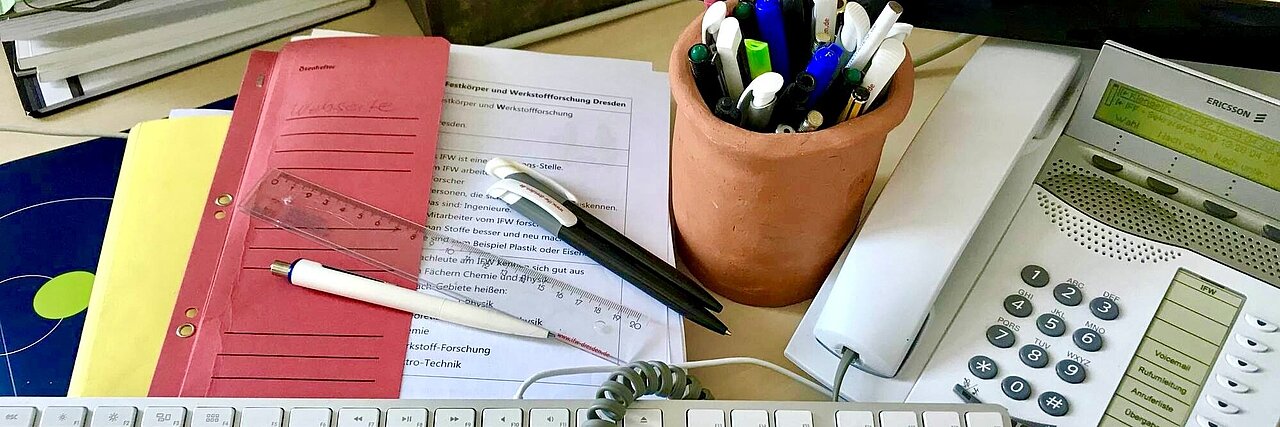 Office worker's desk with keyboard, telephone, pen holder, folders, and documents.