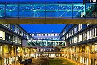 IFW Dresden IFW Gebäude in Dresden: Blick in den Innenhof des IFW Dresden mit beleuchteten Glasbrücken zwischen den Gebäuden bei Abenddämmerung.