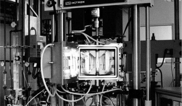 An open-top high-temperature furnace mounted in an Instron test frame.