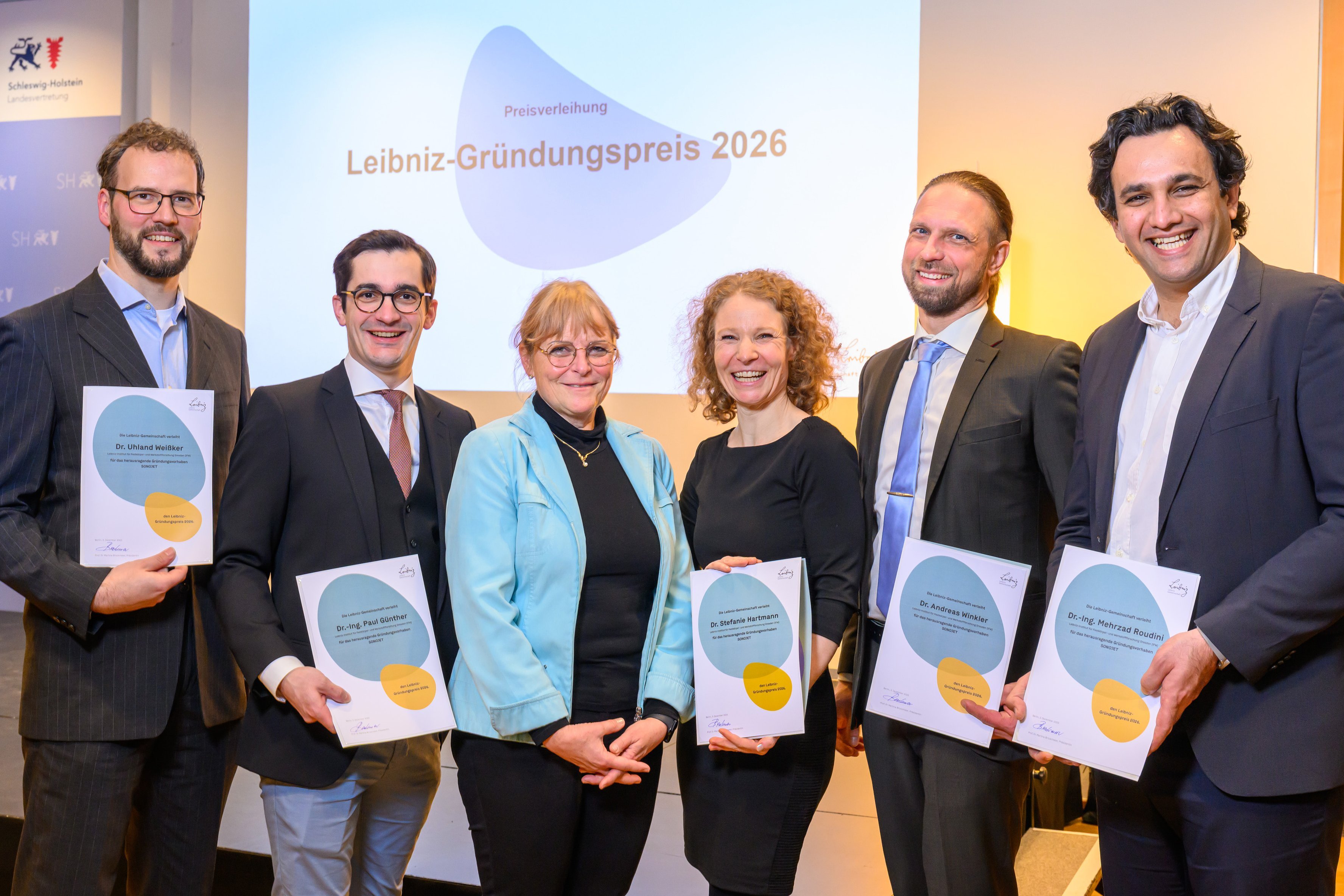 Eine Menschengruppe mit einer Auszeichnung zum Leibniz-Gründungspreis in den Händen.