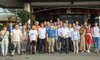 Die Teilnehmenden der Konferenz haben sich zu einem Gruppenbild aufgestellt. 27 Personen stehen in zwei Reihen vor einem Gebäude.