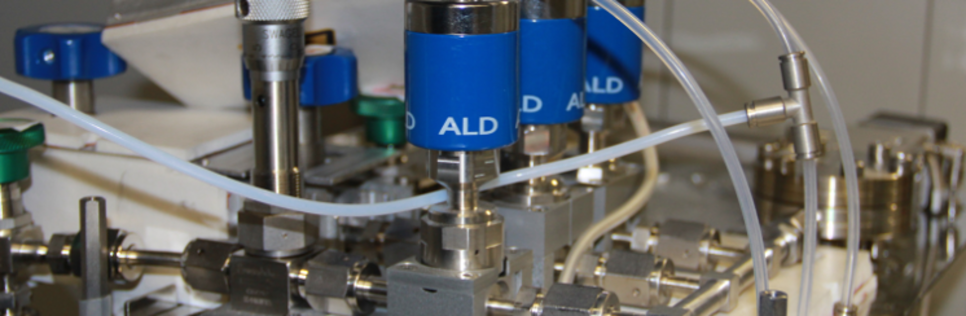 Close-up of a technical device with multiple blue cylinders connected by white tubes labeled 'ALD'