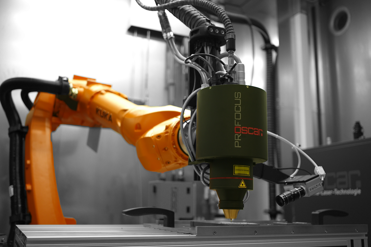 Industrial robot arm with a laser attachment for deposit welding of metals in a manufacturing environment.