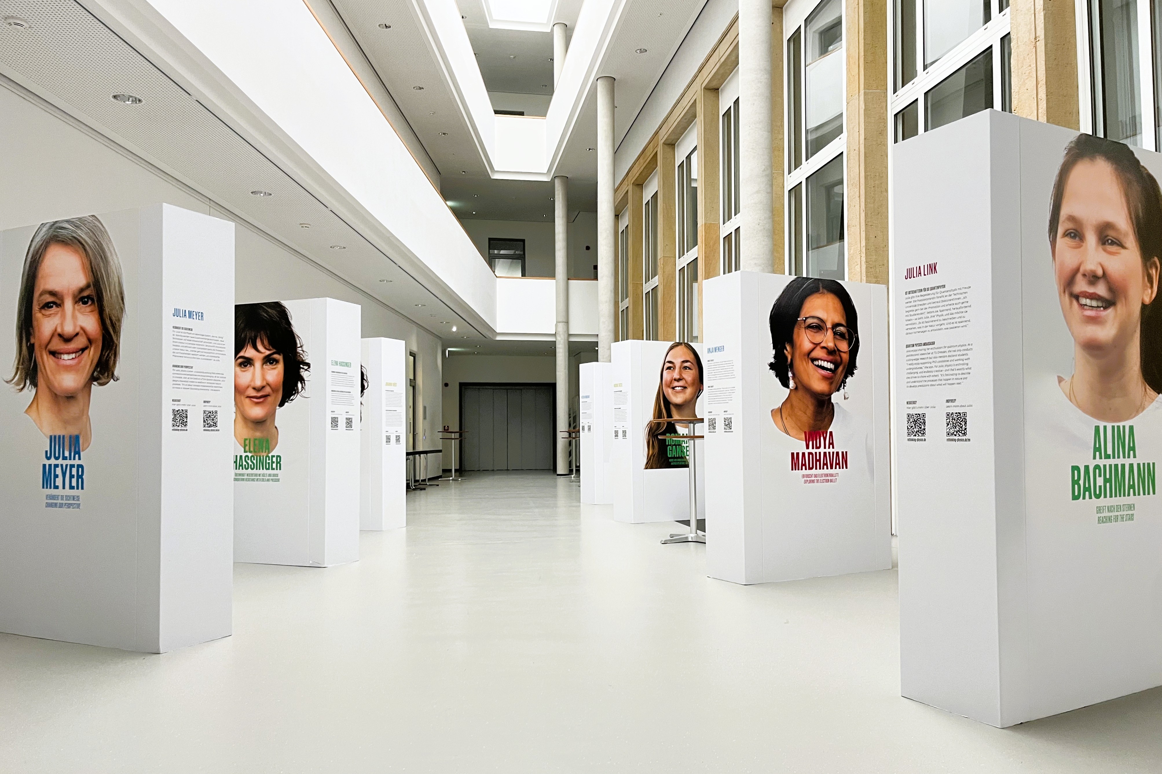 Mehrere große Papp-Stelen mit Bildern von Porträts verschiedener Frauen stehen im Atrium des IFW Dresden.